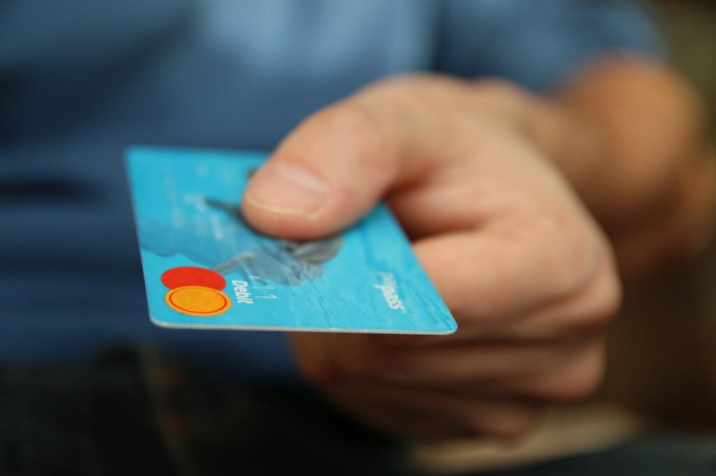 money-card-business-credit-card-50987-1 A close-up shot of a hand offering a blue debit card for payment.