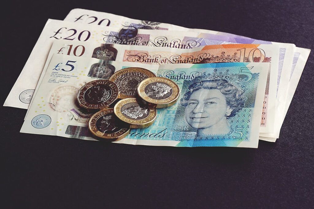 pexels-photo-1791583-1 High-quality image of British pound notes and coins on a dark surface, showcasing currency detail.